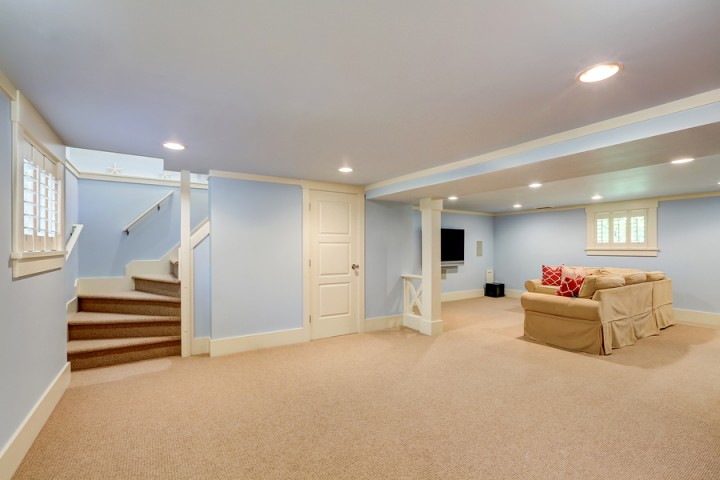 Finished basement family room with beige carpet, blue walls, stairs, and sectional sofa